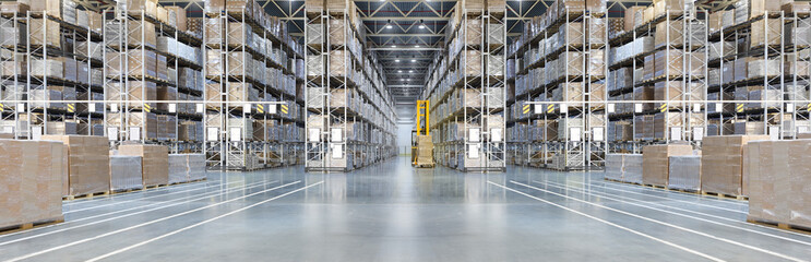 Warehouse with large high shelving showing boxes and a worker driving a forklift in the middle aisle